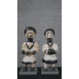 Two primitive carved African figures of warriors, with painted details, one holding a tool and one