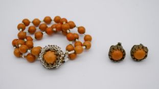 A pair of amber bakelite floral design clip earrings and matching bracelet by Miriam Haskell, makers