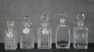 A collection of five cut crystal and glass decanters with stoppers, three with ceramic drinks