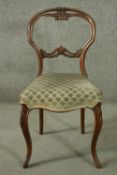 A 19th century walnut side chair, with a carved saddle back, above an overstuffed seat upholstered