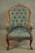 A Victorian walnut spoon back armchair, upholstered in patterned blue fabric, with a buttoned