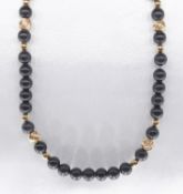 An obsidian and 14k gold bead necklace. Strung with fifty three round polished obsidian beads