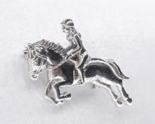 A silver brooch in the form of a horse and female rider. Secure hinged pin to the back with safety