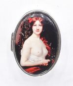 An oval silver pill box with an enamel panel to the top depicting a nude female. Stamped sterling.