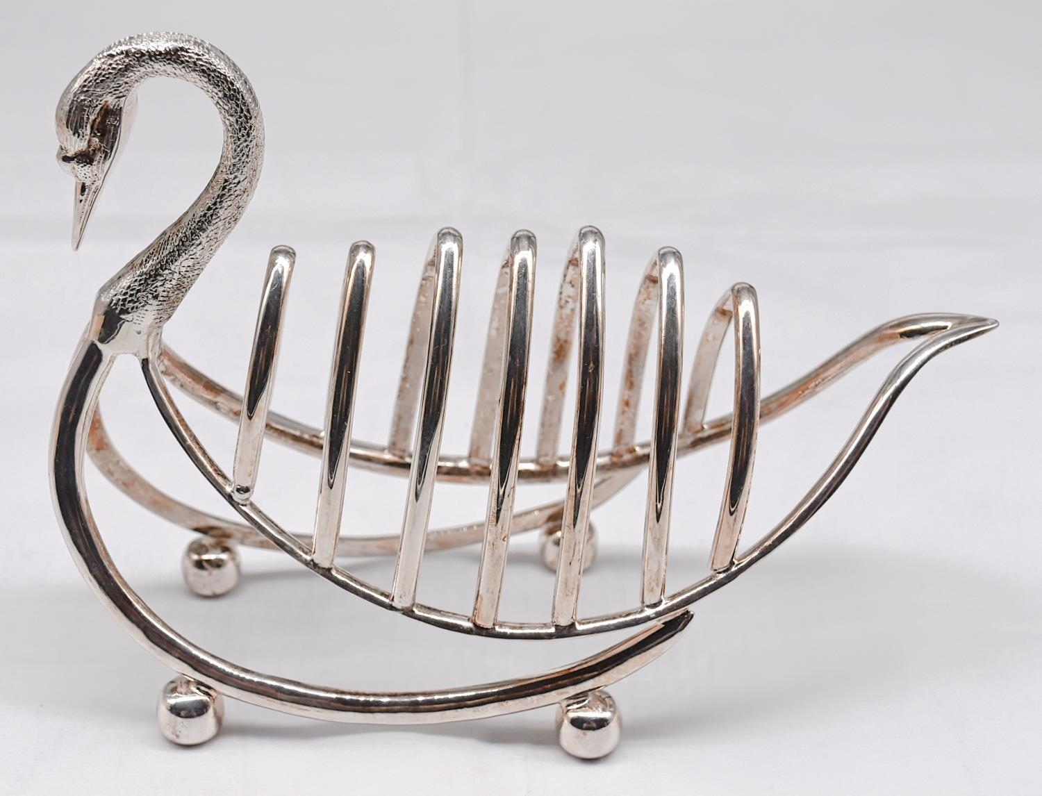 A silver plated toast rack in the form of a swan, with engraved detailing to the head. Sits on - Image 2 of 3