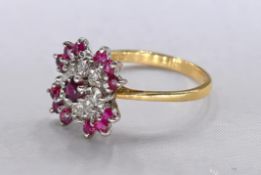 An 18 carat yellow gold, ruby and diamond flower ring. Set with thirteen round mixed cut rubies with