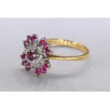 An 18 carat yellow gold, ruby and diamond flower ring. Set with thirteen round mixed cut rubies with
