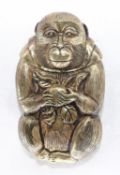A brass vesta case in the form of a Japanese monkey holding a peach.