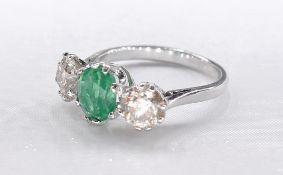 An 18 carat yellow gold emerald and diamond three stone ring. Set to centre with a round brilliant