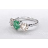 An 18 carat yellow gold emerald and diamond three stone ring. Set to centre with a round brilliant