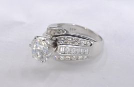 A 14 carat white gold and diamond dress ring. Set to centre with a round brilliant cut diamond in