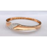 A vintage 14 carat yellow gold and diamond hinged bangle with twist design. The central panel set