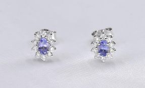 A pair of 18ct white gold and tanzanite cluster earrings. The two earrings set with oval mixed cut
