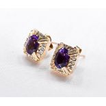 A pair of 14 carat yellow gold amethyst and diamond earrings. Each earring set with an oval mixed