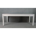 A contemporary white painted wood dining table, of rectangular form, on square section legs. H.75