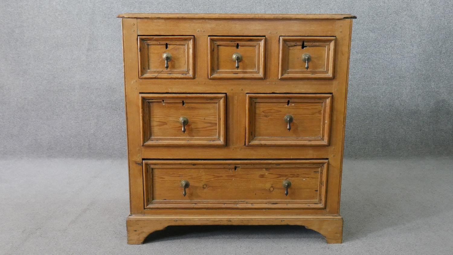 An 18th century pine chest, with a plank top above three short, over two short, over one long