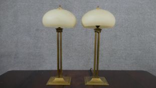 A pair of 20th century brass table lamps, with mushroom form shades, on four reeded columns