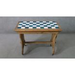 A late 19th century pine occasional table, with blue and white chequerboard tiled top, on end