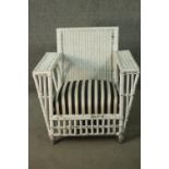 A white painted rattan garden armchair, of woven construction, with a black and white upholstered