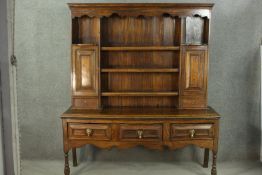 An 18th century country dresser, with three shelves flanked by two panelled cupboard doors and two