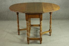 An early 20th century oak drop leaf table, the oval top with a moulded edge, on turned gatelegs,