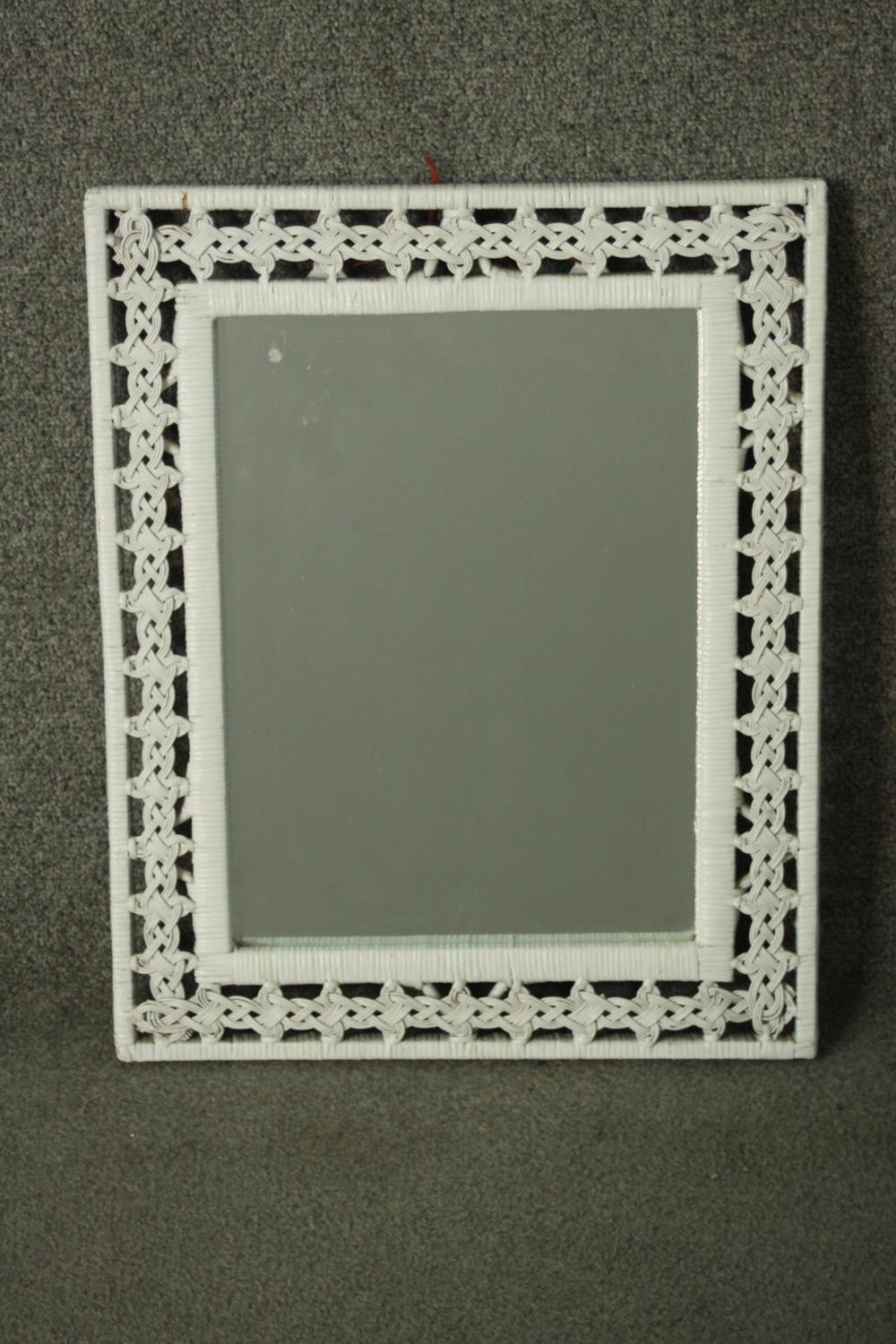 A white painted woven rattan framed mirror, with a rectangular mirror plate. H.53 W.43cm.