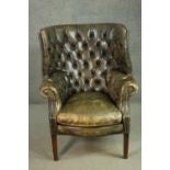 A green leather barrel back armchair, with a buttoned back and arms, on square section tapering
