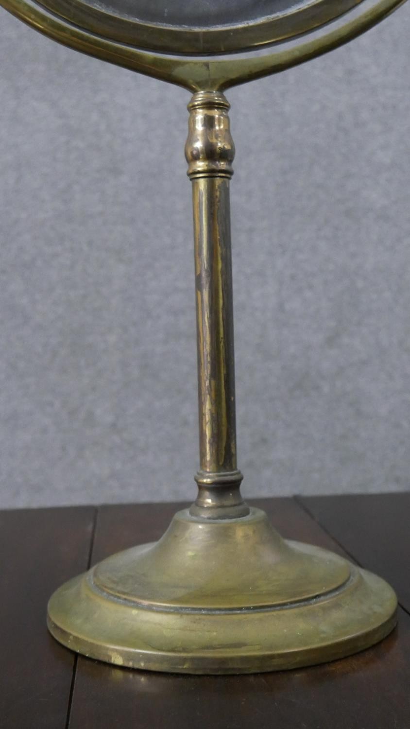 A large 20th century brass swing frame toilet mirror, with an oval mirror plate, on a circular base. - Image 6 of 6