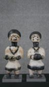 Two primitive carved African figures of warriors, with painted details, one holding a tool and one