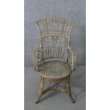 A wicker open arm conservatory chair, the back with cross and spiral detail, the arms with scrolling