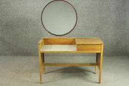 An E Gomme G-Plan oak dressing table, with a circular mirror, over a white recess, flanked by a