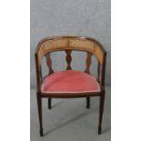 An Edwardian mahogany tub chair, with a caned back rest, over a pink velour seat, on square
