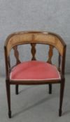 An Edwardian mahogany tub chair, with a caned back rest, over a pink velour seat, on square