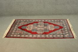 A Pakistan Bokhara red ground handmade rug. L.165 W.98cm.