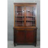 An early 19th century mahogany bookcase, with a gadrooned cornice over two glazed cupboard doors