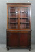 An early 19th century mahogany bookcase, with a gadrooned cornice over two glazed cupboard doors