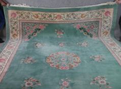 A Chinese carpet with central floral medallion and spandrels on a jade ground within stylised
