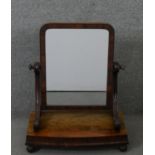 A William IV mahogany swing framed toilet mirror, the rectangular mirror on scrolling supports,