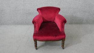 A late Victorian tub armchair, upholstered in pink velour, on turned walnut legs.