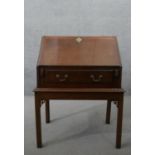 A George III mahogany bureau on stand, the fall front opening to reveal a central door,