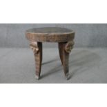 A carved tribal hardwood occasional table, with a circular top, the splayed legs each carved with