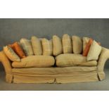 A contemporary three seater sofa, upholstered in ochre fabric, with scrolling arms and a selection
