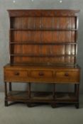 An 18th century oak dresser, the plate rack with three shelves, over three short drawers, on ionic