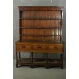 An 18th century oak dresser, the plate rack with three shelves, over three short drawers, on ionic