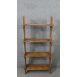 A set of pine open bookshelves, the four shelves joined to the shaped side with pegs. H.121 W.60 D.