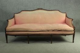 An Adam style mahogany three seater sofa, the top rail centred by a carved urn, upholstered in