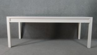 A contemporary white painted wood dining table, of rectangular form, on square section legs. H.75