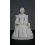 A Minton Parian ware model of an elderly lady seated in an armchair, a book open on her lap.