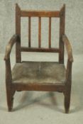 An early 19th century rustic elm child's armchair, the back with three spindles and open arms,