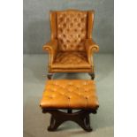 A tan leather wing back armchair with footstool, the chair with a buttoned back and scrolling